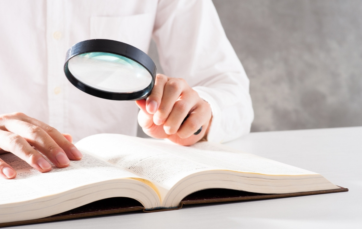 辞書をルーペで見ている人の写真