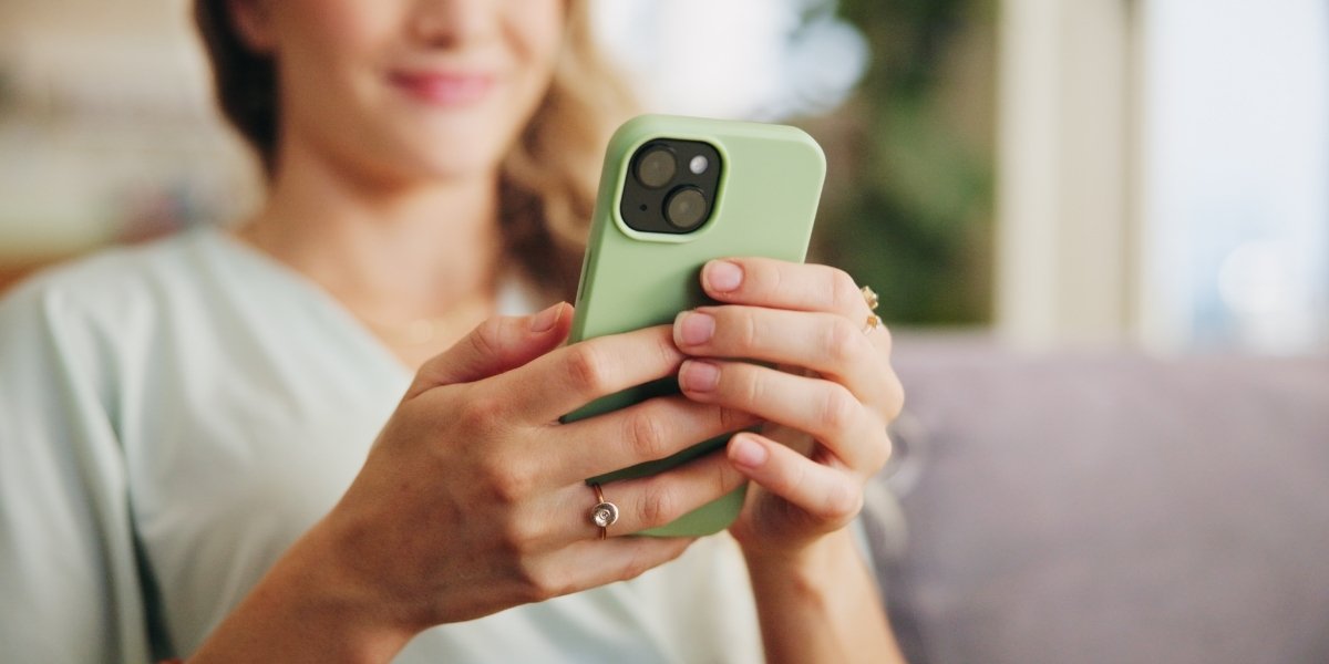 スマホを見ながら微笑む女性の写真