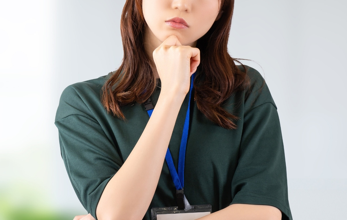 社員証を首から下げて考える女性の写真