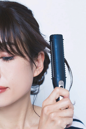 ストレートアイロンで後れ毛を巻いている写真