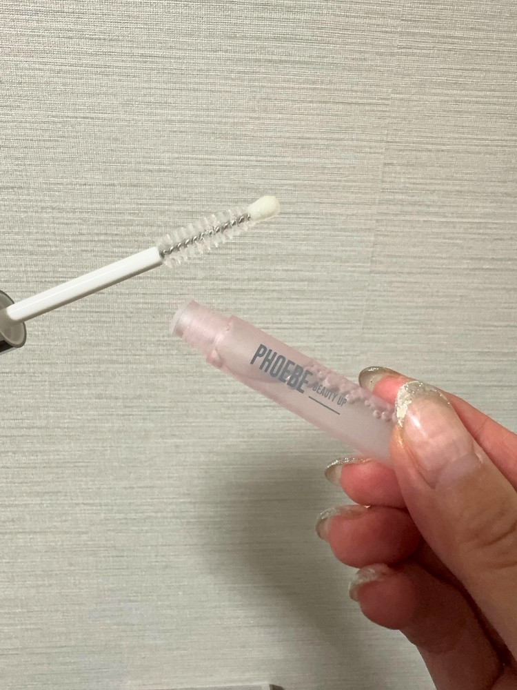 まつ毛美容液のふたを開けてブラシを出している写真