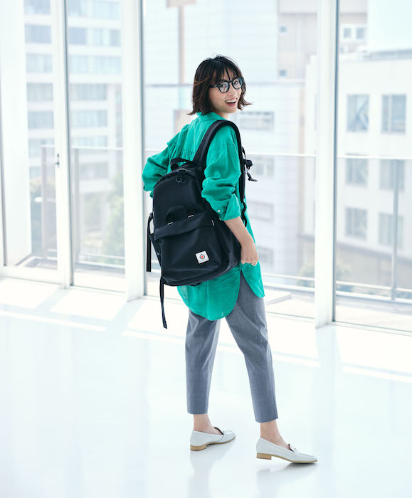 グリーンシャツ×グレーテーパードパンツ×黒リュックコーデのバックショット