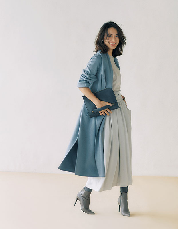 淡いグレーのTシャツとスカートにくすんだ水色のロングコートをはおったモデル写真