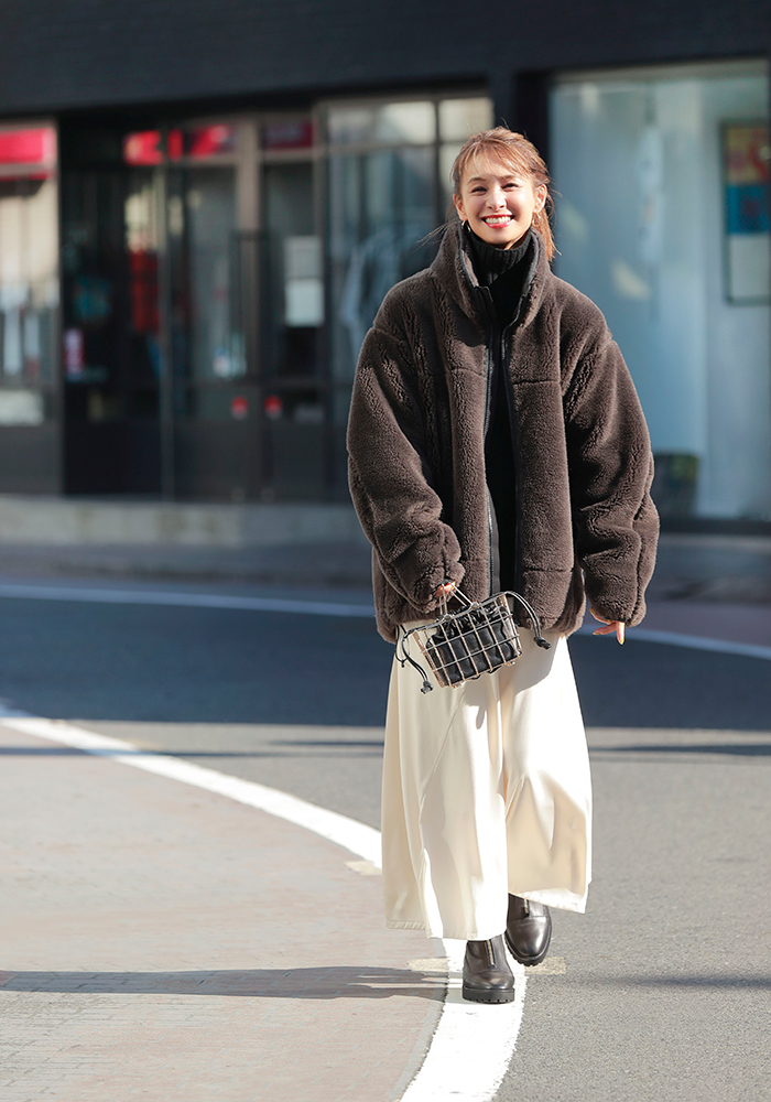 黒のタートルネックニットと白のロングスカートに茶色のミディアム丈のボアブルゾンをはおったモデル写真