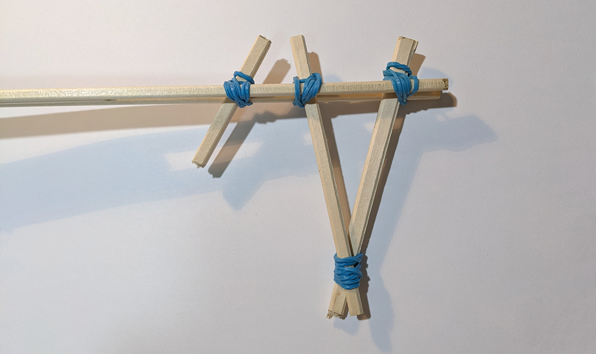 先ほどつくったグリップの少し前に短く切った割り箸を輪ゴムでとめた写真 短く切った割り箸は右肩上がりの向きでとめられている