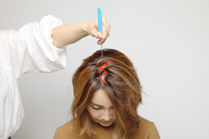 コームの柄で分け目をジグザグにしているボブヘアの写真