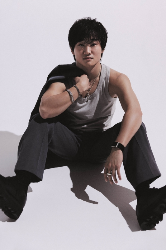 グレーのノースリーブシャツに黒パンツ、左肩にジャケットを携えた角田選手の写真