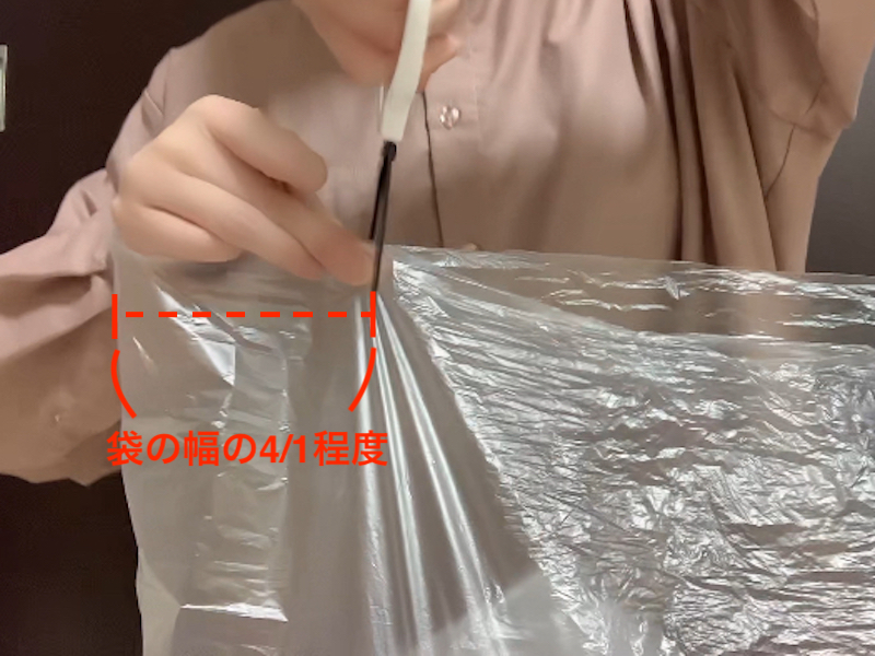 取っ手のないゴミ袋の上部にハサミで切れ込みを入れている様子