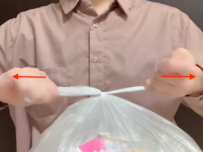 ゴミ袋の簡易取っ手を結んだ後に引き締める様子