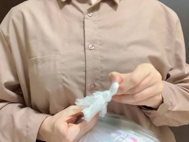 ねじったゴミ袋上部の輪から残りを引き出す様子