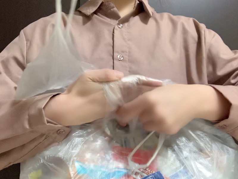 ゴミ袋の小さい取っ手を持ってくるくると折る様子