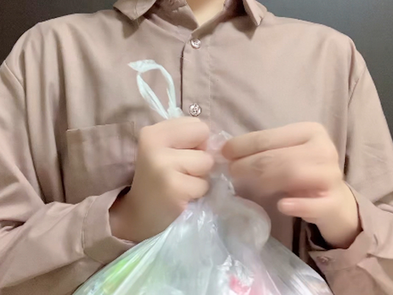 口を折ったゴミ袋の大きい取っ手を固結びする様子