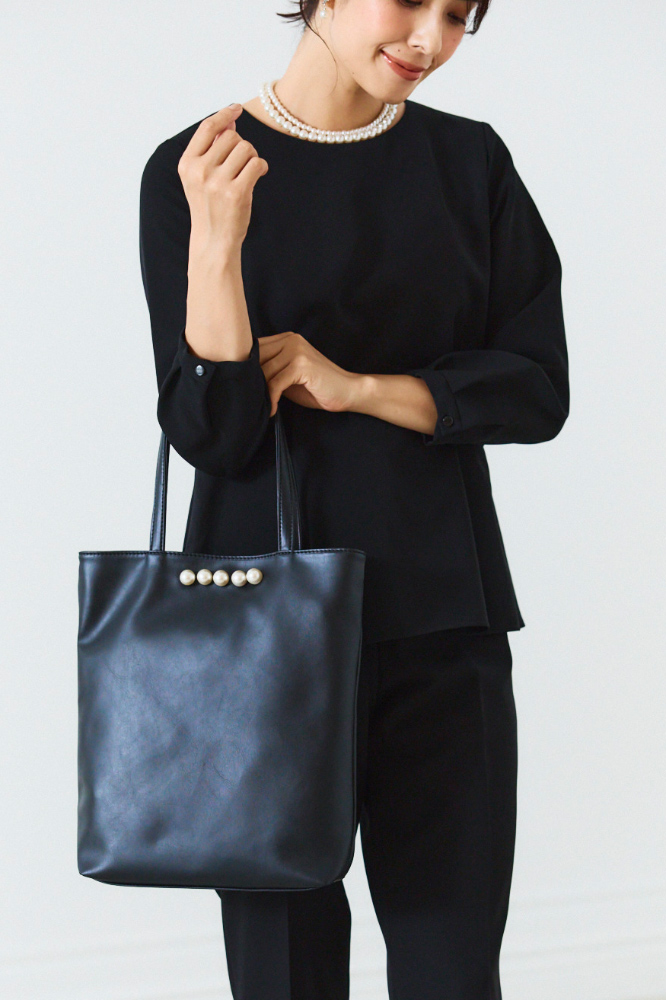 黒のパール付きハンドバッグを持った人