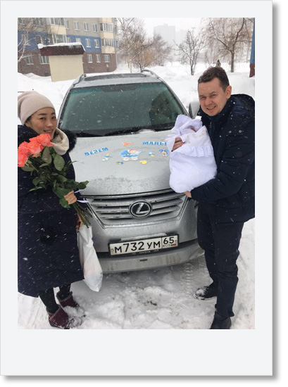 雪の積もった街、車、夫婦と新生児