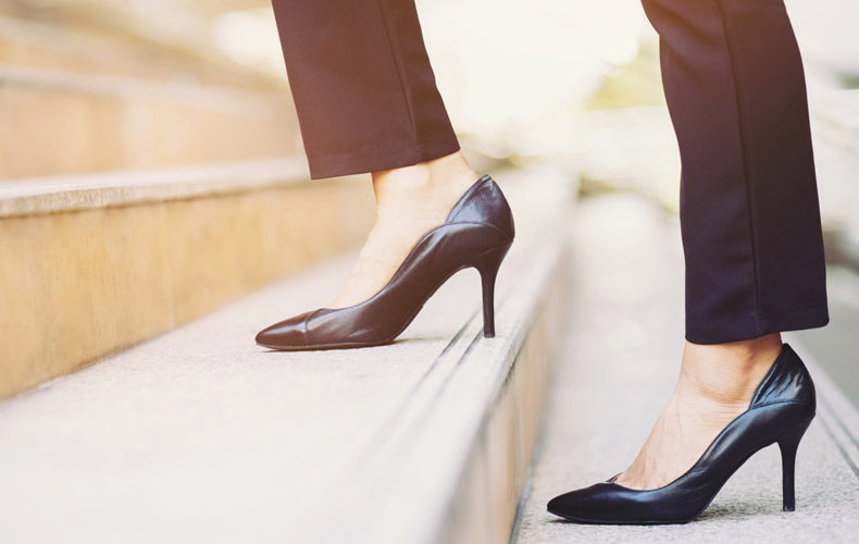 ヒールの高いパンプスを履いて階段をのぼる足元