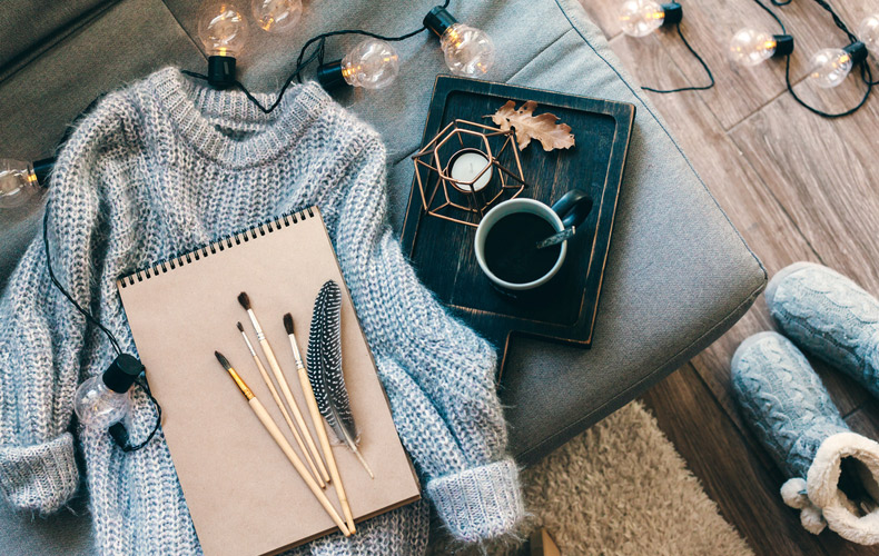 ソファの上にセーターやコーヒーカップが置いてあるのを上から見た写真