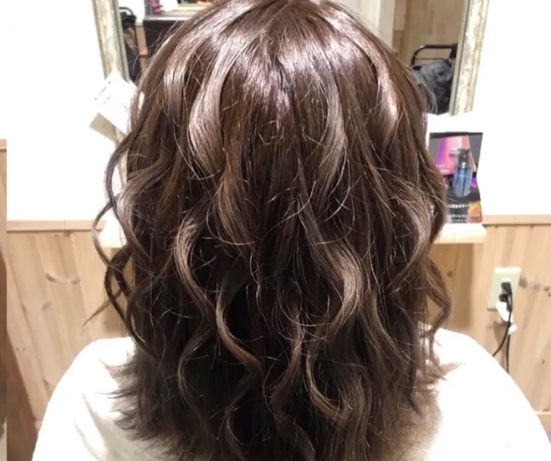 髪表面にウェーブがかかった長めのボブヘアの後頭部写真