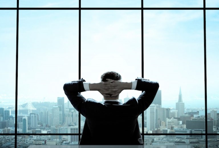 窓に向かって腕を頭の後ろで組む男性