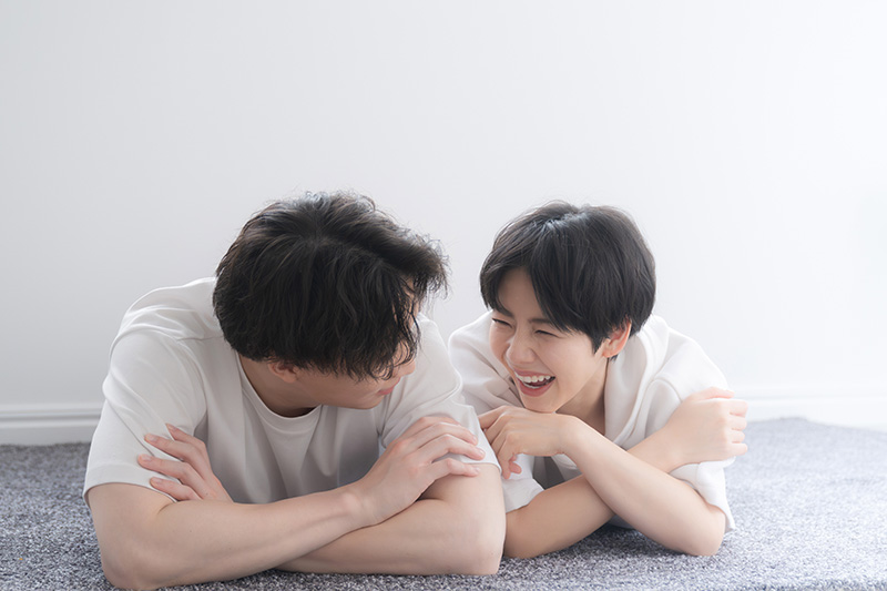 寝転がって見つめ合うカップル