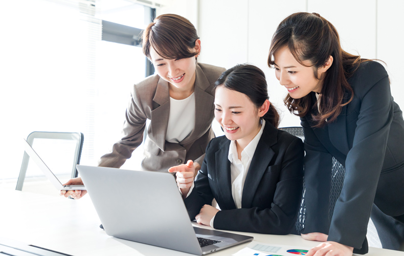PCを見て笑顔のビジネスウーマン3人の写真