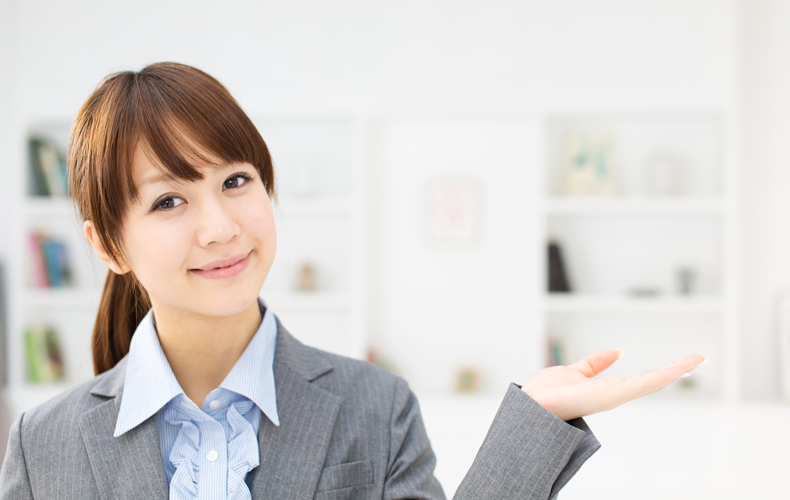 案内するポーズをとるビジネスウーマンの写真