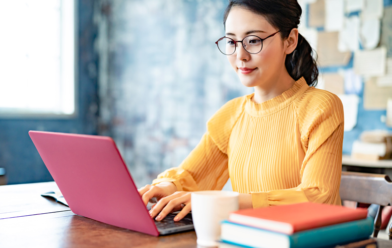 ノートパソコンで作業する女性の写真
