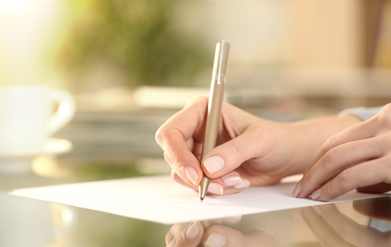ペンで紙に手紙を書く手元の写真