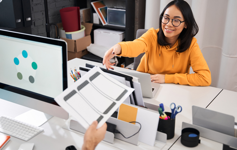 資料を向かいのデスクの女性に渡している写真