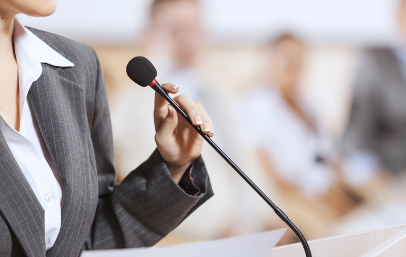 マイクの前に登壇するスーツ姿の人