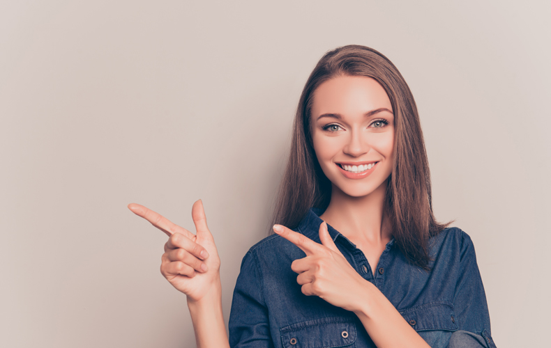 両手で右を指差す笑顔の女性