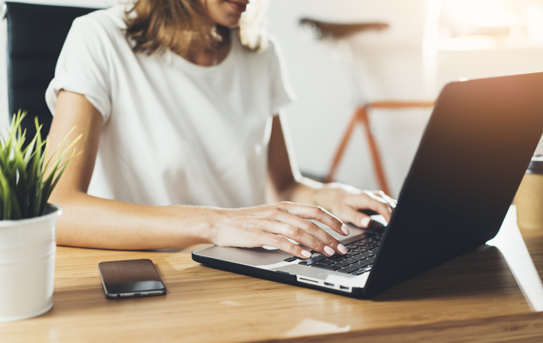 ノートパソコンで在宅ワーク中の女性の写真