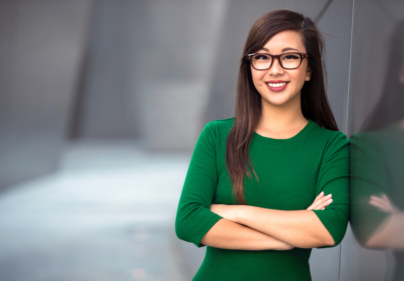 腕を組んで微笑みながら壁に寄りかかる人の写真