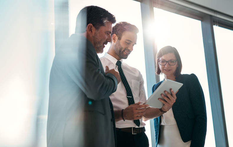 タブレットを見ながら社内打ち合わせをしている