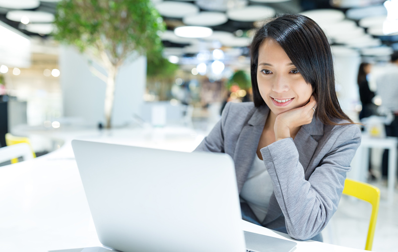 笑顔でノートパソコンを見ているビジネスウーマンの写真
