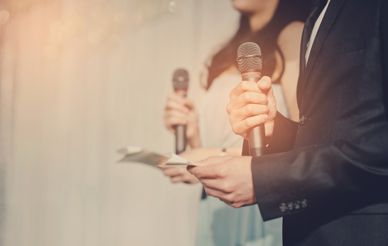 マイクと原稿を持って立っている男女の写真