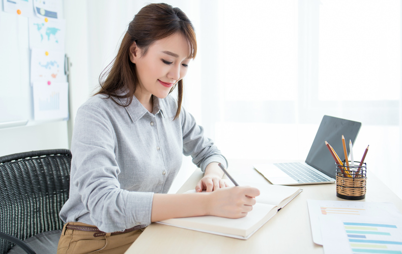 オフィスでノートに何か書いている女性の写真