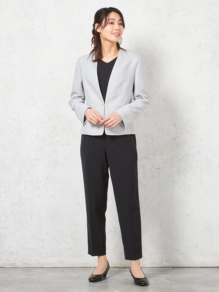 シンプルなブラウス、パンツとノーカラージャケットを着用したモデル