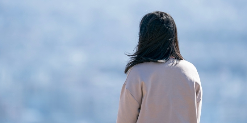 海を眺める女性の後姿の写真