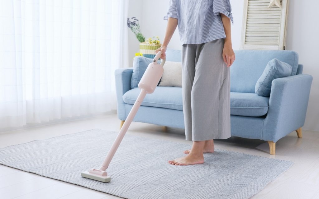 カーペットに掃除機をかける女性の写真