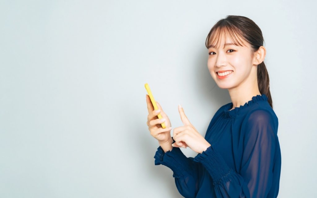 スマホを操作する笑顔の女性の写真