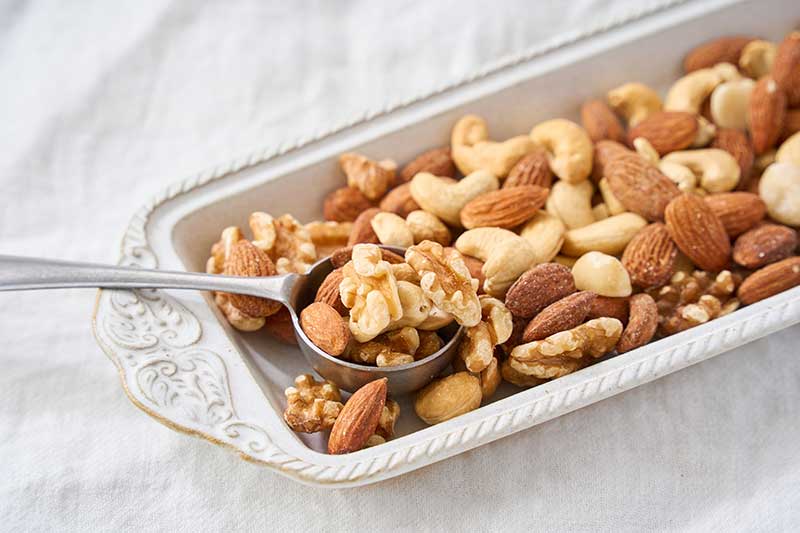 お皿に盛られたナッツをスプーンですくう