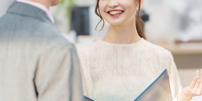 職場の男性と笑顔で話す女性の写真