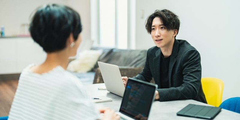 職場で会話する男女の写真