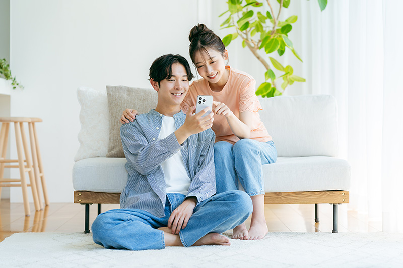 リビングでくつろぎながらスマホを見るカップル