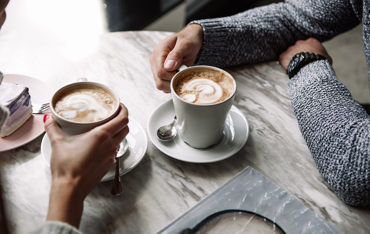 男女が向き合って座り、コーヒーカップを持っている様子