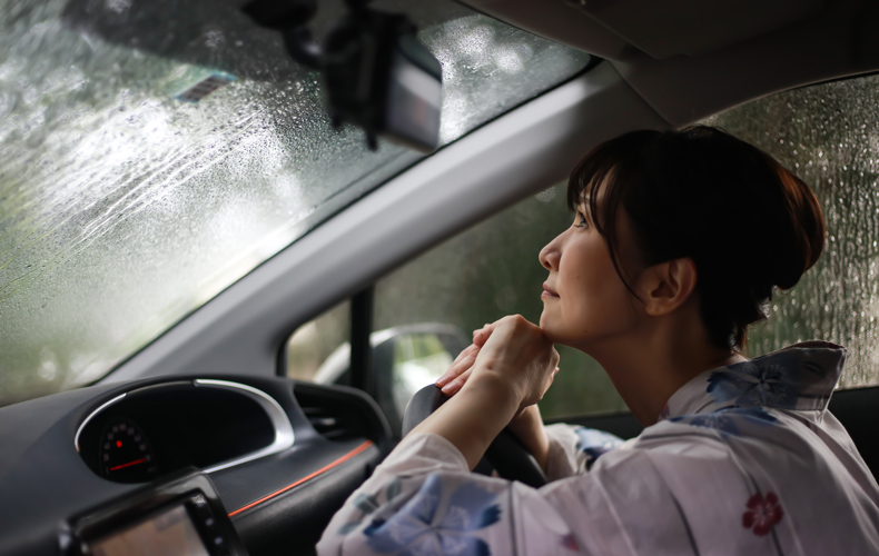 車の中で雨宿りする浴衣姿の女性