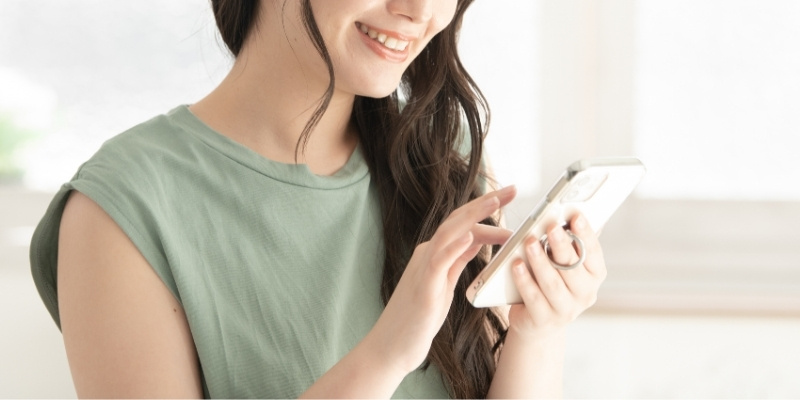 笑顔でスマホを操作する女性の写真