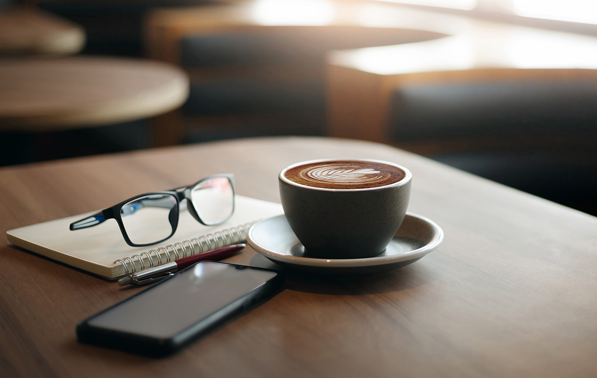 テーブルに置かれたコーヒーとスマートフォン