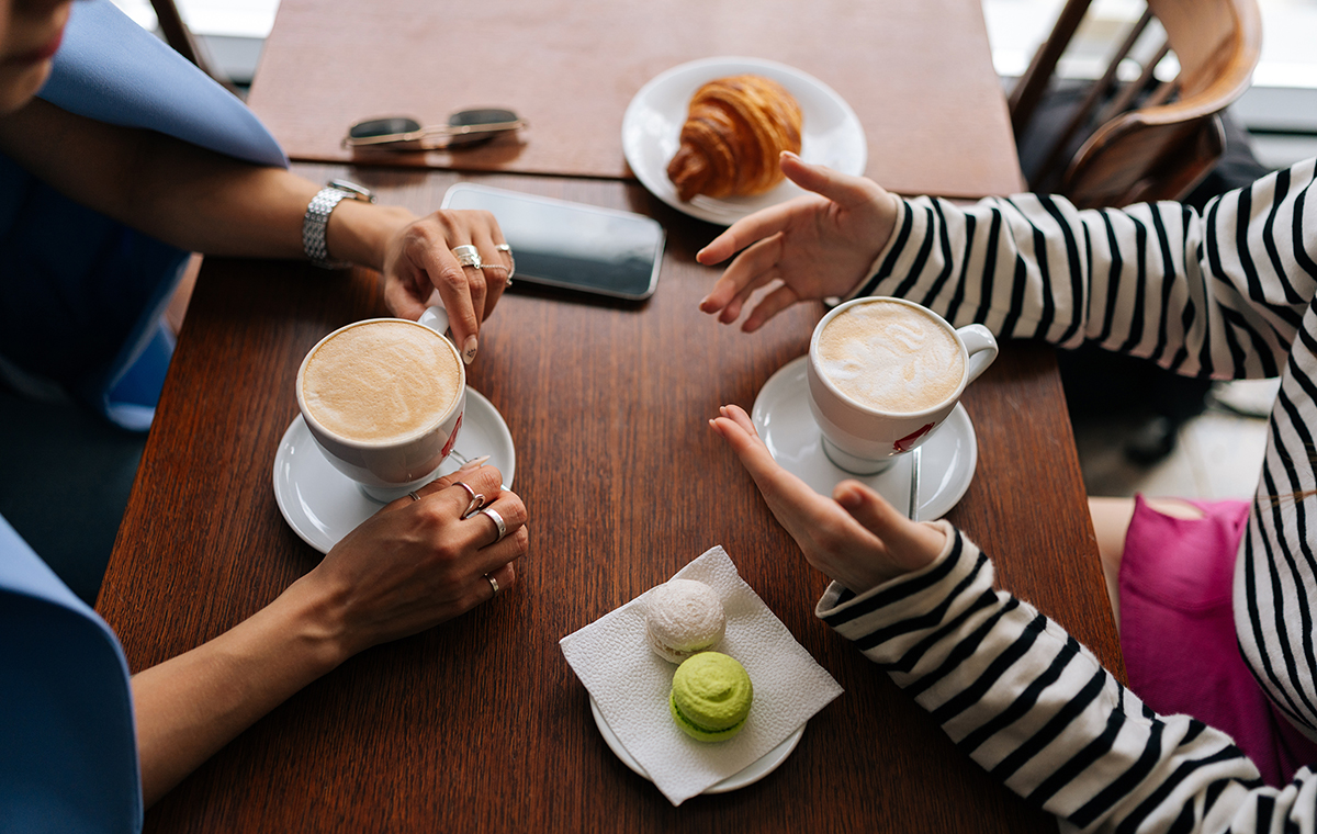 コーヒーカップを持ち向き合って会話をする女性2人