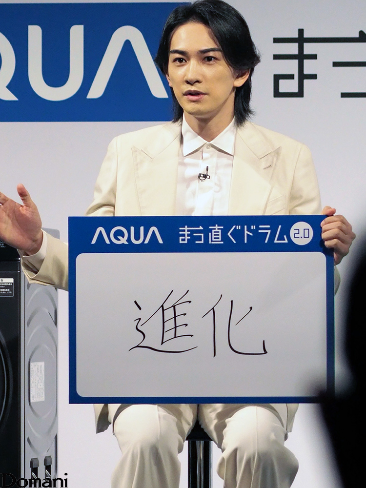 「進化」と書かれたボードを持つ町田啓太さん
